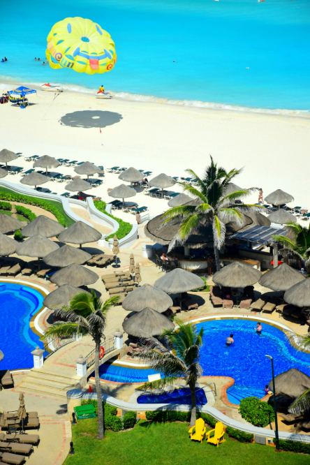 Beach with lounge chairs, 2 pools, a walking path, and a parachute landing on the beach